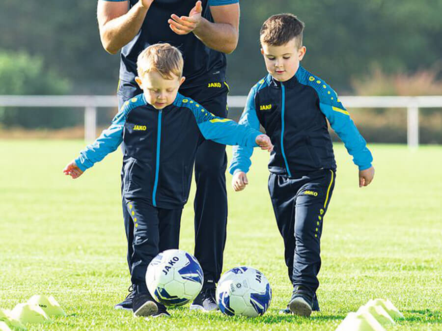 A group of children with the youth coach in JAKO tracksuits