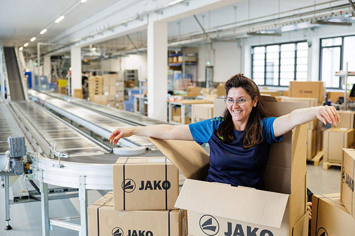 Mitarbeiterin von JAKO im Versandbereich mit JAKO-Kartons