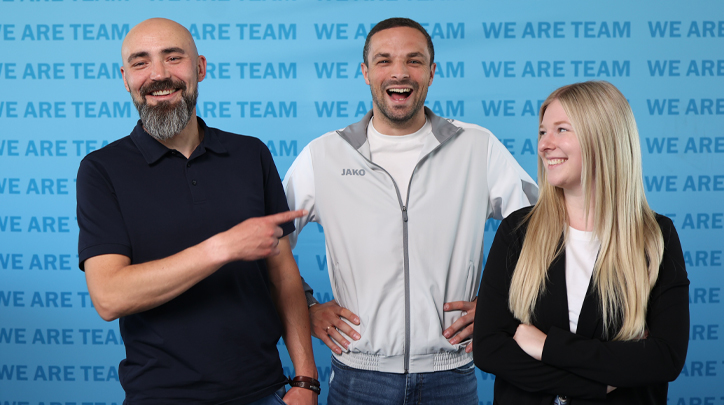 Jako Teammitglieder vor der Pressewand mit dem Slogan WE ARE TEAM